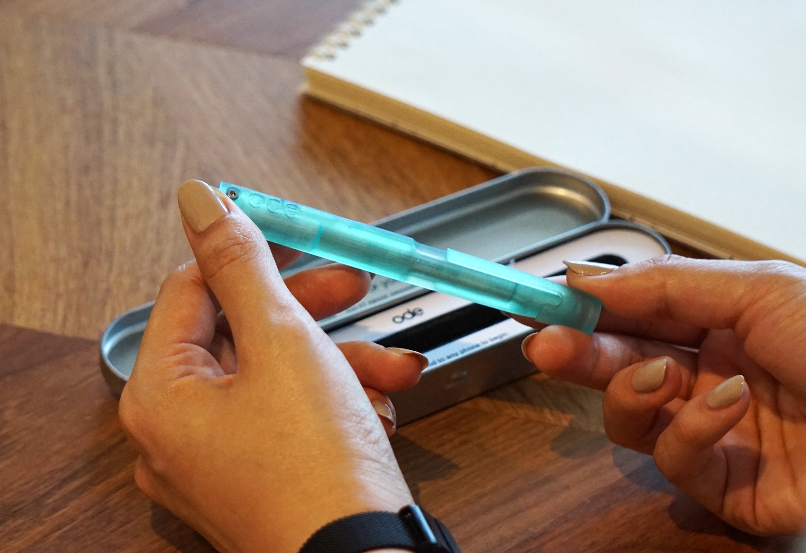 Holding the emerald Ode Pen above its open tin